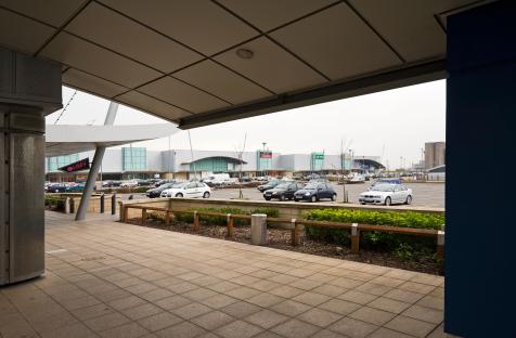 View of a retail park parking lot from under a covered walkway.