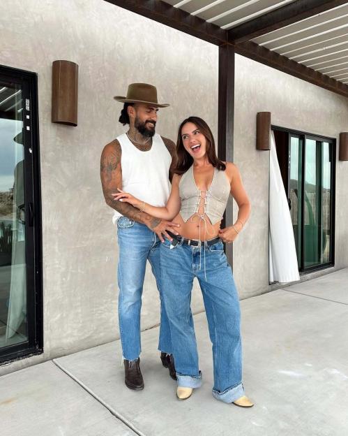 A happy couple stands outside.