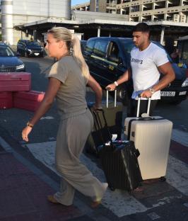 Molly Mae and Tommy Fury arriving at an airport with luggage.