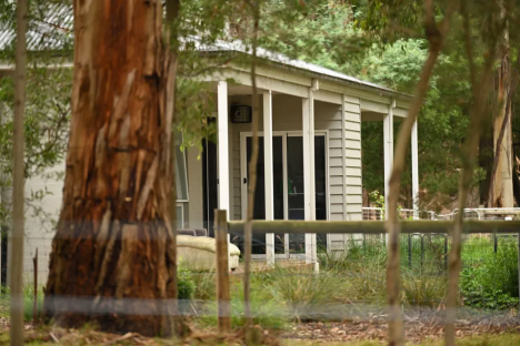 House viewed through trees and fence.