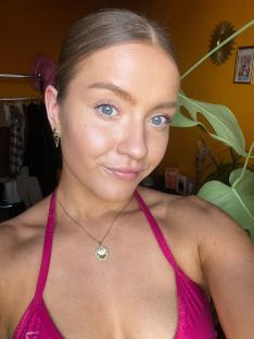 Woman wearing a pink top and gold necklace.