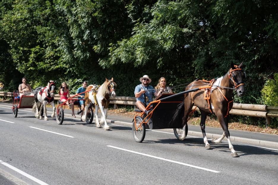 A group of people riding in horse-drawn carriages on a road.