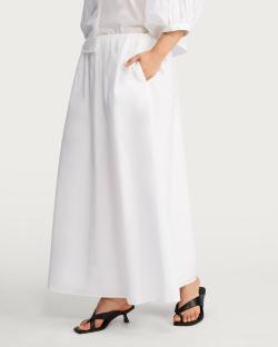 Woman wearing a white maxi skirt and black heels.