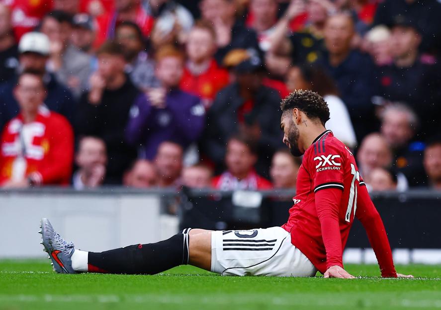 Matheus Cunha of Manchester United sitting on the ground injured during a game.