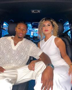 Couple in white outfits sitting in a car.