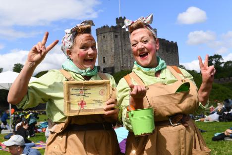 Two women dressed in WWII-era costumes at a VE Day event.
