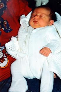 Sleeping baby girl in white outfit.