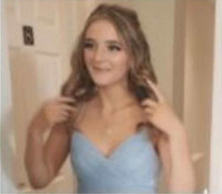 Woman in light blue dress adjusting her hair.