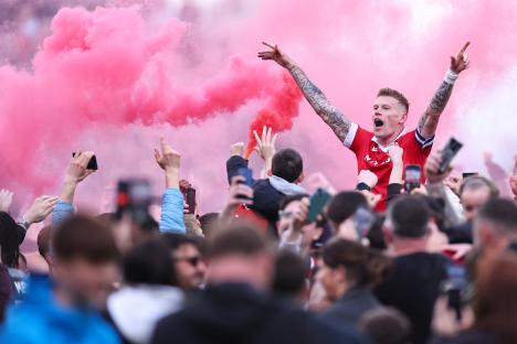 Wrexham AFC players celebrating with fans on the pitch after winning promotion.