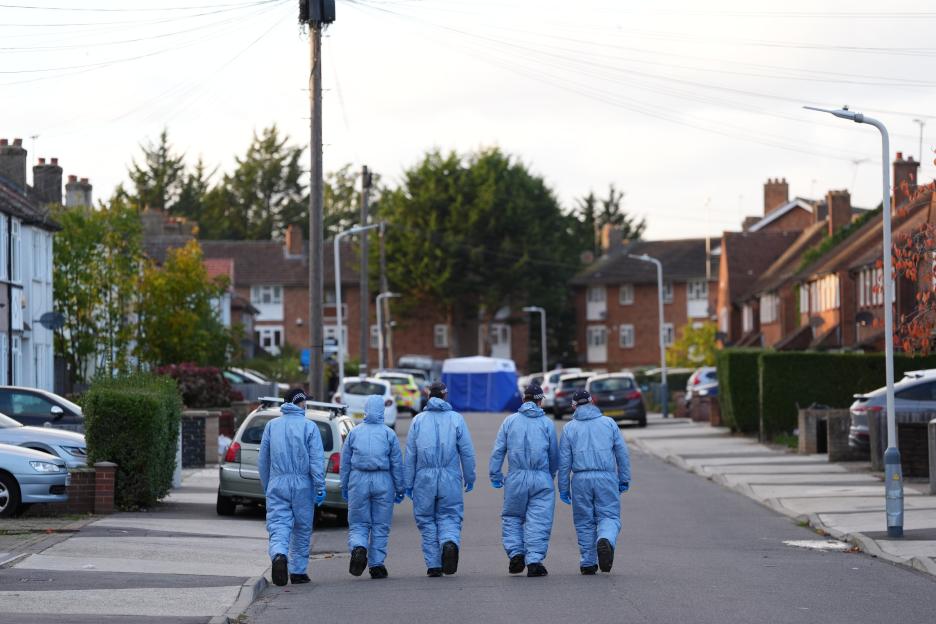 Police officers in Midhurst Gardens, Uxbridge, wearing light blue forensic suits and caps, investigating a crime scene.