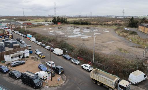Aerial view of a derelict industrial site with parked cars and a dump truck.