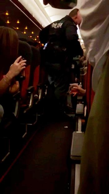 A disruptive passenger clutching a vodka bottle being dragged off an EasyJet flight.