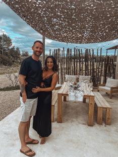 Couple standing together outdoors near a table set for a meal.