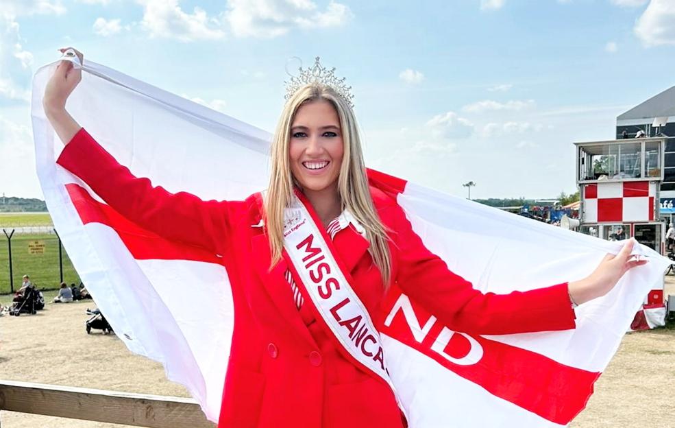 Tabitha Bennett, a beauty queen wearing a red coat and a "Miss Lancaster" sash, holding a large white flag with red accents.