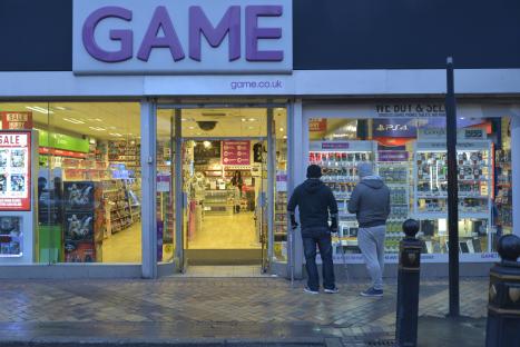 Two people looking at a Game store window in Stockport, England.