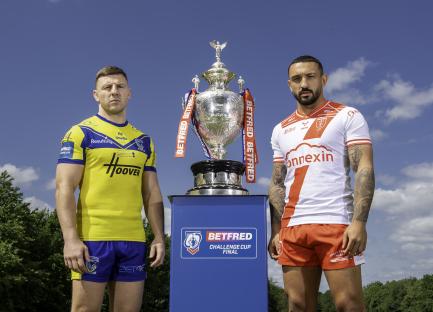 Two rugby players standing on either side of the Betfred Challenge Cup.