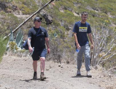 a man wearing a blue shirt that says berghaus walks with another man
