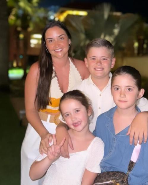 A woman posing with three children.