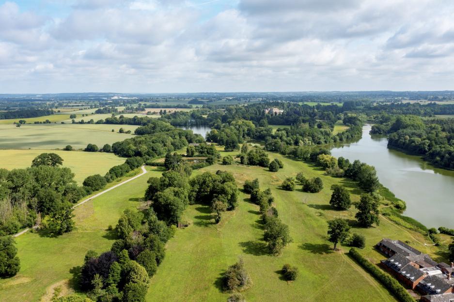 Aerial view of Patshull Park, Shropshire, featuring rolling countryside, a lake, and a hotel.