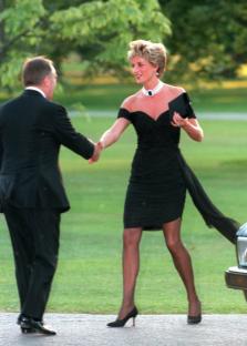 Princess Diana in a black dress shaking hands with a man.