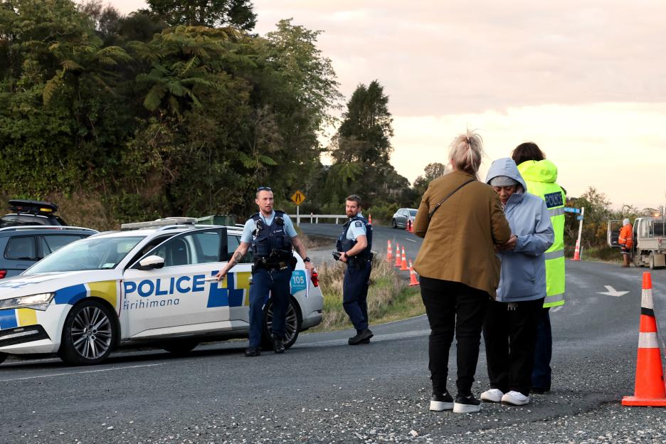 Police officers and civilians at a roadblock following a police shootout.
