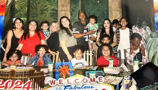 Family photo of a man with five wives and their children.