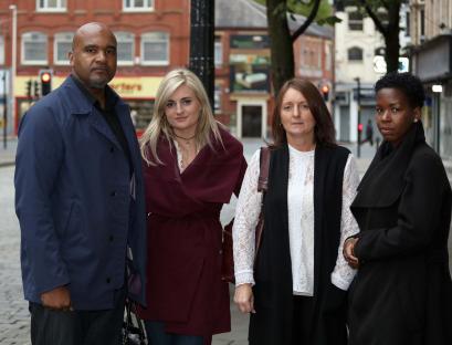 Four people stand outside, possibly at a coroner's inquest.