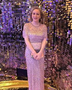 Woman in beaded gown standing in front of sequined wall.