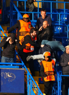 Stewards assisting a person in a stadium.