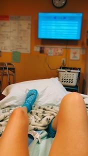 Woman's legs in hospital bed wearing blue socks.