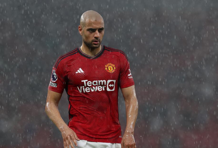 a man wearing a red teamviewer jersey stands in the rain