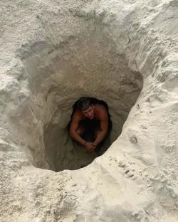 Man sitting in a sand hole.