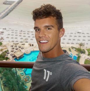Selfie of Gaz Beadle on a balcony overlooking a resort pool and beach.