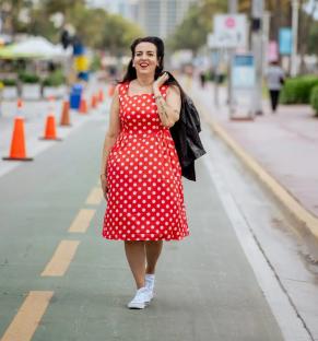 Woman in red polka dot dress walking down a street.