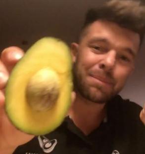 Man holding a halved avocado.