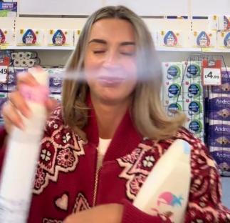 Woman in a red cardigan spraying air freshener in a store.