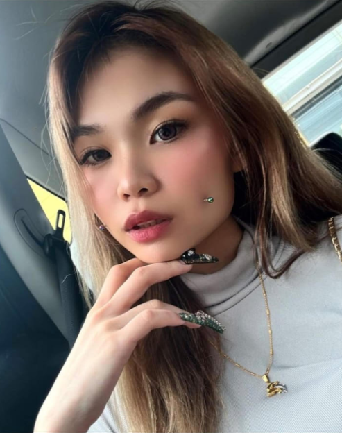 Woman with long brown hair, makeup, and facial piercings.