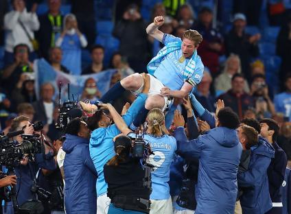 Kevin De Bruyne of Manchester City being lifted in celebration by his teammates.