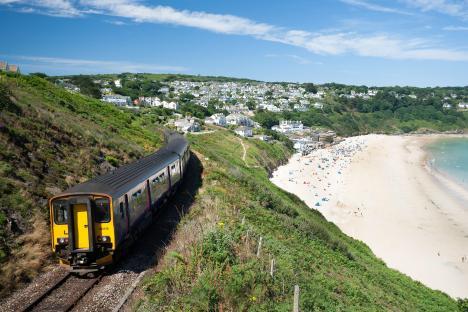 Train traveling along a coastal railway line overlooking a beach.