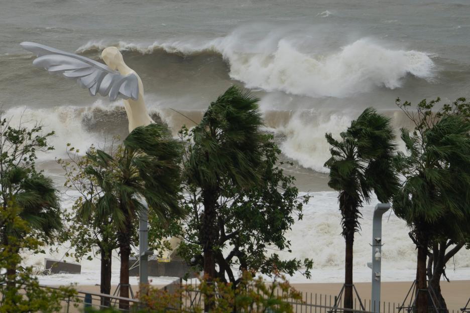 Waves crash onto a beach near a giant winged sculpture in Shenzhen.
