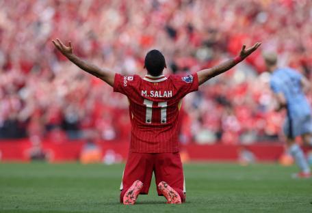 Mohamed Salah celebrates on his knees, arms raised.