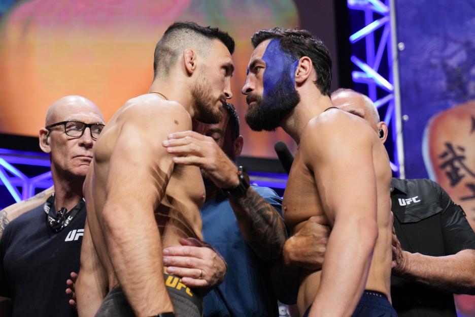 Two UFC fighters face off at a weigh-in.