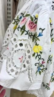 Close-up of embroidered white top with floral details and lace trim.