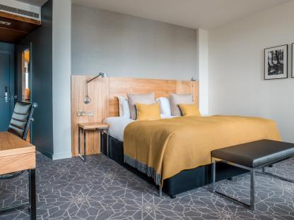 Hotel room with a king-size bed and a work desk.