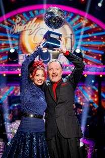 Dianne Buswell and Chris McCausland holding the Strictly Come Dancing trophy.