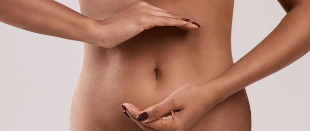 Woman's hands gently cradling her abdomen.