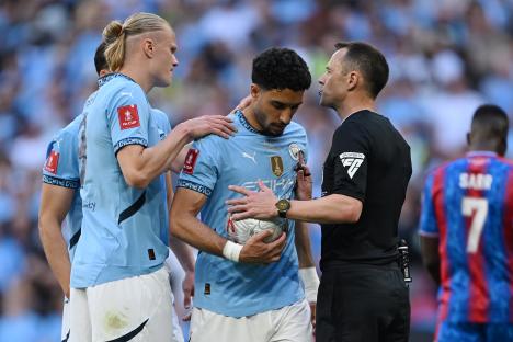 Manchester City players interacting with a referee during a soccer match.