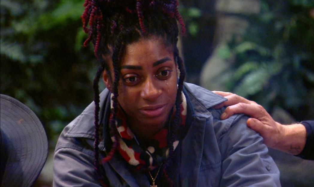Kadeena Cox from "I'm a Celebrity Get Me Out of Here!" with tears in her eyes as a hand rests on her shoulder.