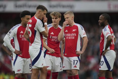 Arsenal soccer players huddle together on the field.