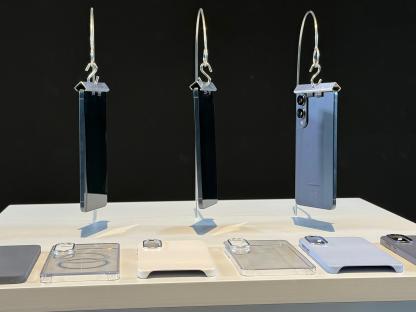 Three smartphones hanging from clips, displayed with various phone cases.